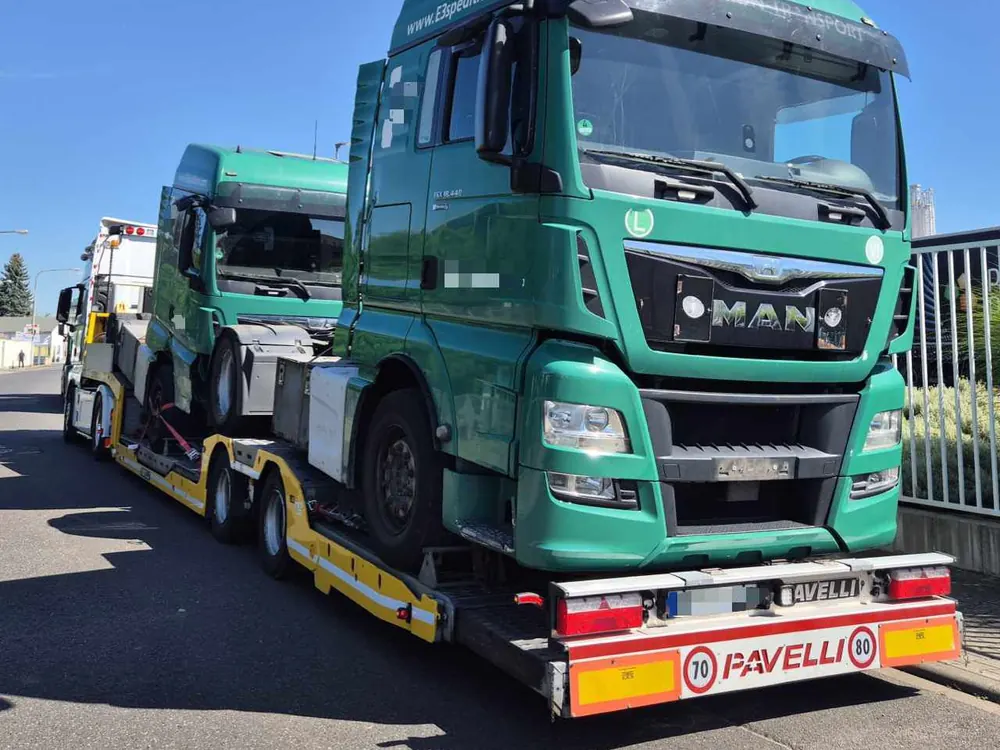 Grüner MAN Lkw auf einem Autotransporter, bereit zur Überführung