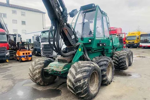 Grüner Harvester mit Kranarm auf dem Betriebsgelände