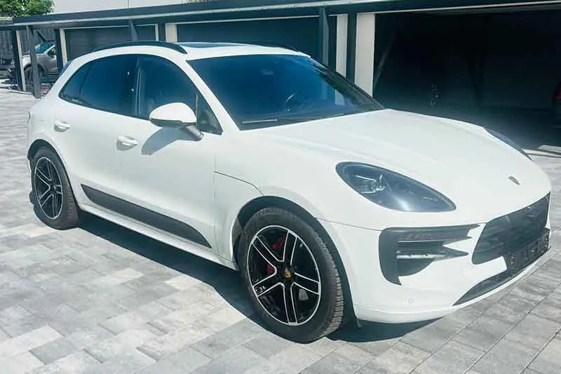 Weißer Porsche Macan vor einer Halle