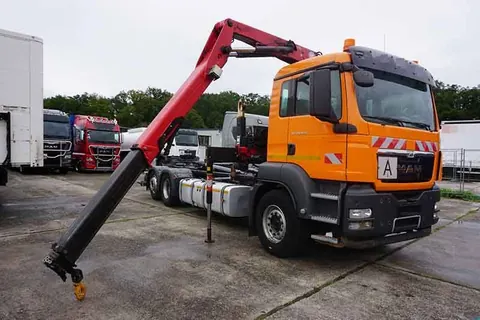 Orangefarbener MAN Lkw mit ausgefahrenem Ladekran