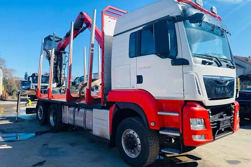 Weiß-roter MAN Holztransporter mit Ladekran
