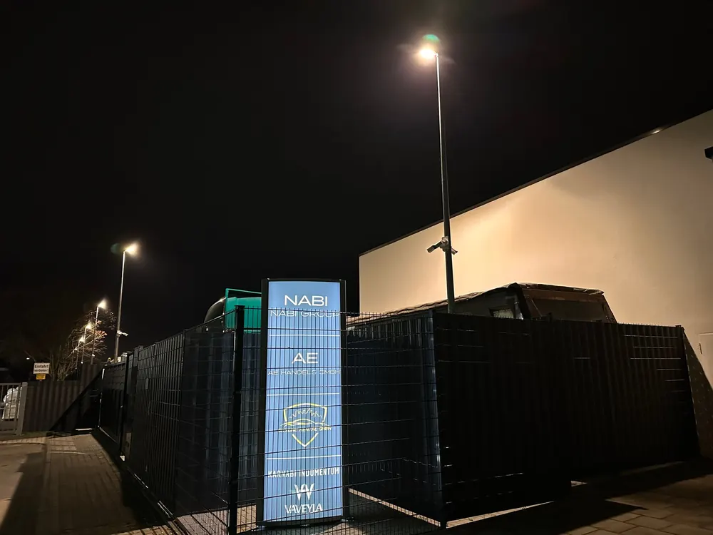 Beleuchteter Hof bei Nacht mit Schild der Nabi Group