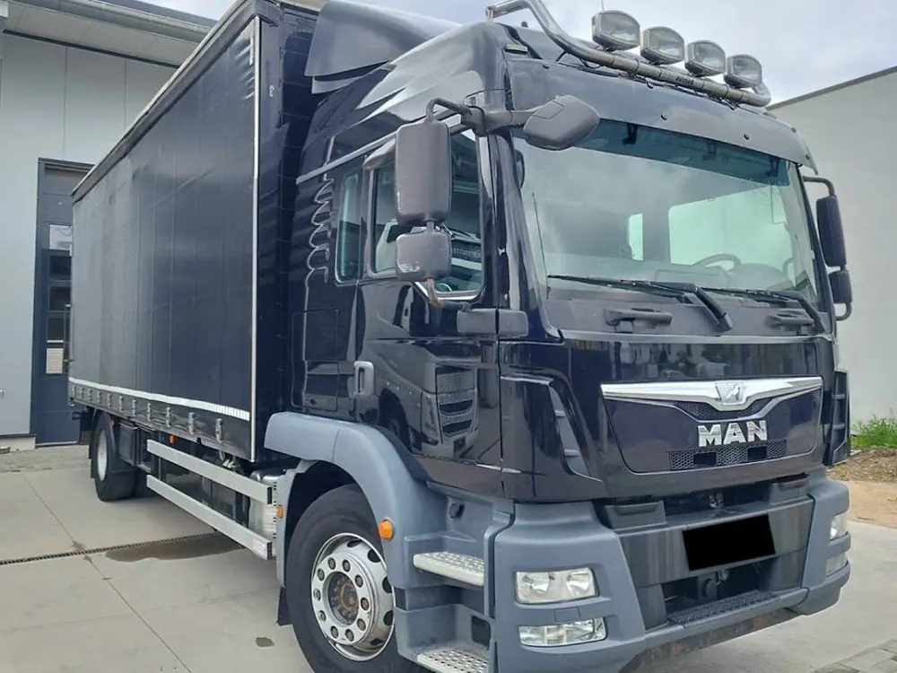 Schwarzer MAN Koffer-Lkw vor dem Firmengebäude